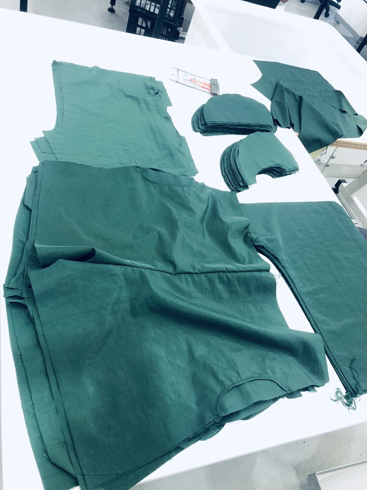 Piles of green fabric cut out into shapes and laid out on a table